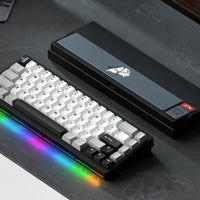 Mechanical keyboard with RGB lighting on a desk with a laptop and gaming accessories.
